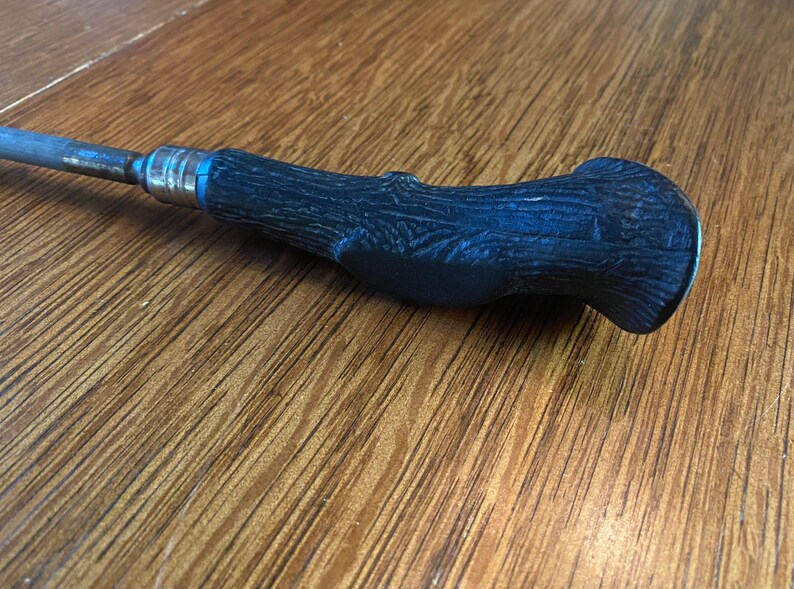 May include: A black metal screwdriver with a wood-grain patterned handle.