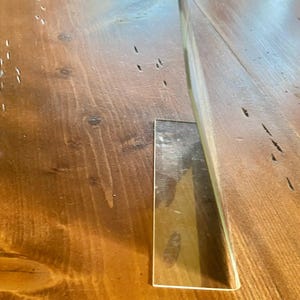 May include: A white ceramic mug with a black handle and the text "But First, Coffee" in a bold, black font. The mug is set against a blurred background, suggesting a cozy setting.