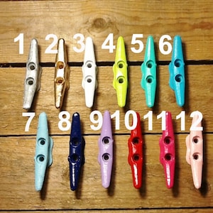 May include: Twelve cleat hooks in various colors, including white, blue, yellow, red, pink, and navy blue. The hooks are numbered 1 through 12.
