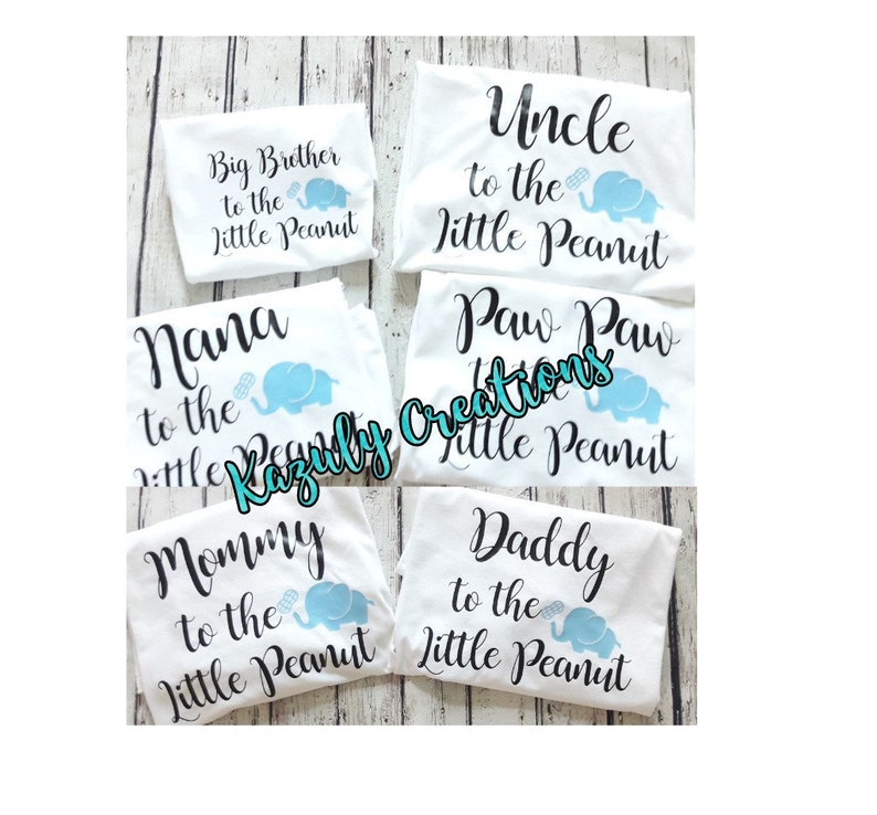 May include: Five white t-shirts with black text and a blue elephant graphic. The shirts read "Big Brother to the Little Peanut", "Nana to the Little Peanut", "Uncle to the Little Peanut", "Paw Paw to the Little Peanut", "Mommy to the Little Peanut", and "Daddy to the Little Peanut".