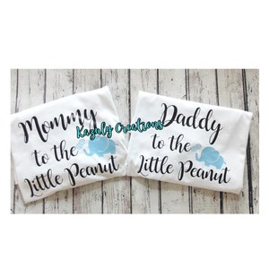 May include: Two white t-shirts with black text and a blue elephant graphic. The text on the left shirt reads "Mommy to the Little Peanut". The text on the right shirt reads "Daddy to the Little Peanut".