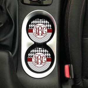May include: Two car coasters with a black and white houndstooth pattern, a red chevron pattern, and a white monogram in the center. The monogram is the letters "B.G."