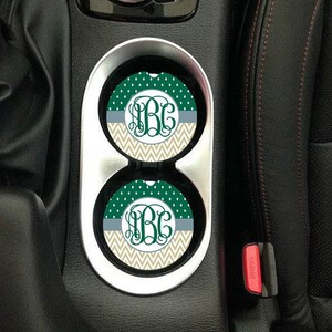 Könnte beinhalten: Zwei grüne und beige Auto-Untersetzer mit einem weißen Zickzackmuster und weißen Punkten. Die Untersetzer haben ein Monogramm in der Mitte, das "B.G." sagt.