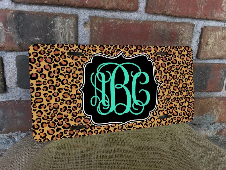 May include: A personalised number plate with a leopard print background and a black and white frame. The monogram "BC" is in teal green.