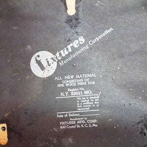 Może przedstawiać: Czarno-biała etykieta z tekstem "Fixtures Manufacturing Corporation" i "All New Material Consisting of 100% Wood Fiber Pad" z numerem rejestracyjnym "N.Y. 23031 MO."