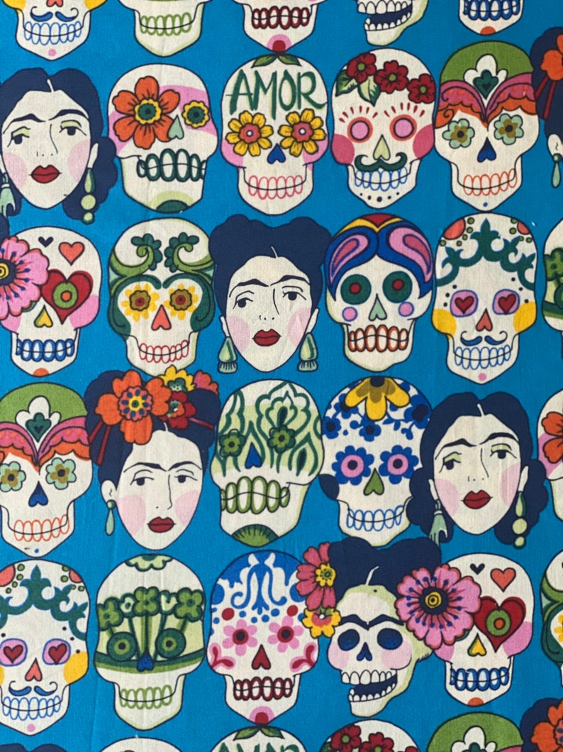 Puede incluir: Una tela azul con un patr&oacute;n repetido de calaveras de az&uacute;car coloridas con flores y la palabra "AMOR" en el centro de algunas de las calaveras.