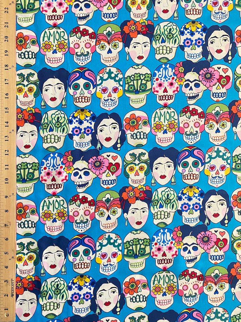 Puede incluir: Una tela azul con un patr&oacute;n repetido de calaveras de az&uacute;car coloridas y dise&ntilde;os florales. Las calaveras tienen la palabra "AMOR" escrita en ellas.