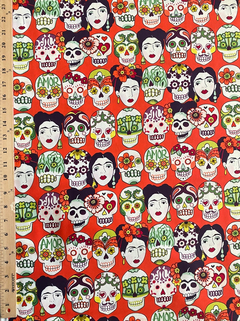 Puede incluir: Una tela roja con un patr&oacute;n repetitivo de calaveras de az&uacute;car coloridas y dise&ntilde;os florales. Las calaveras tienen detalles pintados y el texto "AMOR" aparece en algunas de las calaveras.