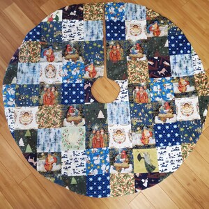 May include: A circular patchwork Christmas tree skirt featuring a variety of fabric squares with printed holiday scenes, including nativity figures, angels, stars, and winter forest landscapes in shades of blue, green, red, and white.