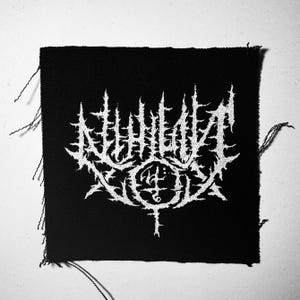 May include: Black and white embroidered patch with the text "NIHILIST" in a stylized font.