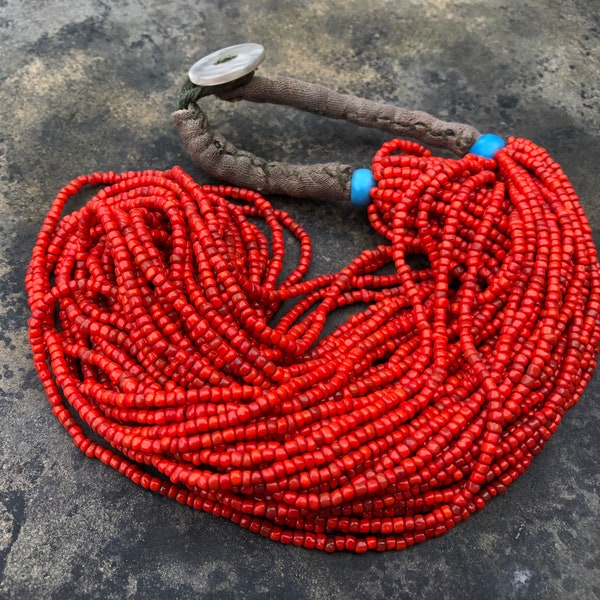 Collier tribal à brins multiples avec de petites perles rouges dessinées, des perles bleues et un emballage en tissu