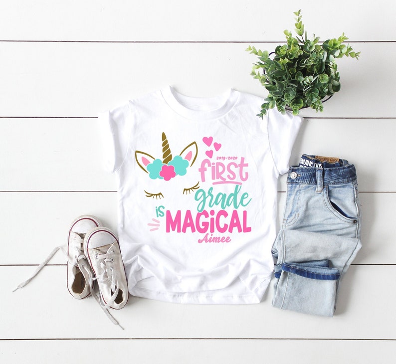 white girls tshirt with pink and blue unicorn and the words first grade is magical, personalized with school year and her name