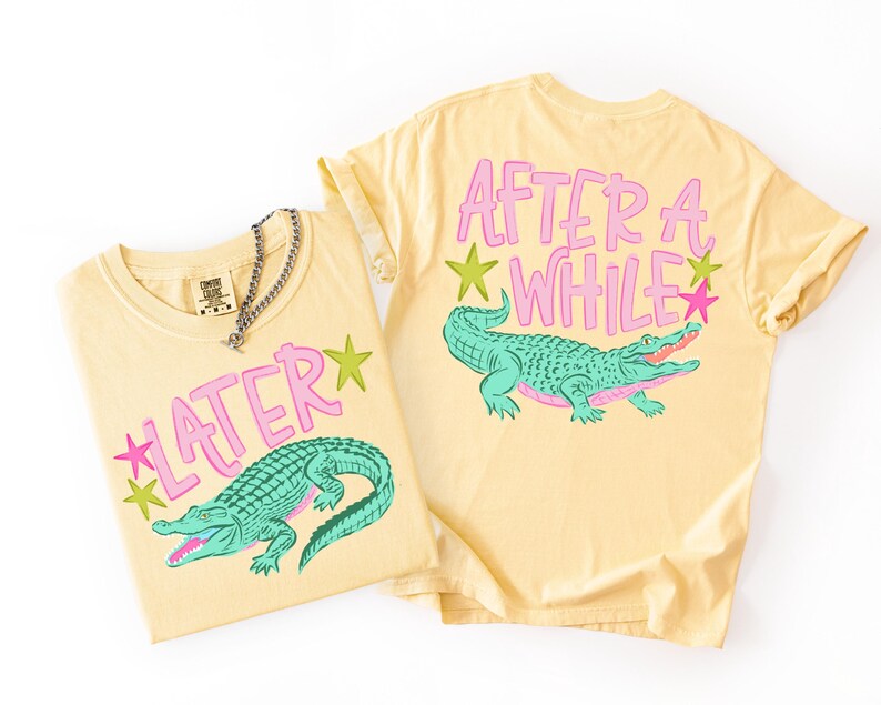 May include: Two yellow t-shirts with alligator graphics. One shirt says "LATER" with a green alligator and pink stars. The other says "AFTER A WHILE" with a green alligator and pink stars. A silver chain necklace is on one shirt.