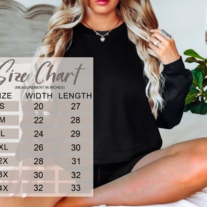 May include: A black sweatshirt with a size chart overlay. The size chart lists measurements in inches for width and length, ranging from size small (20" width, 27" length) to 4X (32" width, 33" length). The sweatshirt is shown on a person.