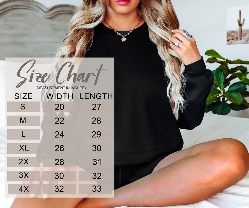 May include: A black sweatshirt with a size chart overlay. The size chart lists measurements in inches for width and length, ranging from size small (20" width, 27" length) to 4X (32" width, 33" length). The sweatshirt is shown on a person.