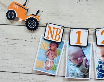 Może przedstawiać: Baner ze zdjęciami dziecka z pomarańczowym wycięciem traktora i zdjęciami oznaczonymi "NB", "1", "2" i "3". Zdjęcia przedstawiają dzieci na różnych etapach. Baner jest zawieszony na sznurku na białym drewnianym tle.