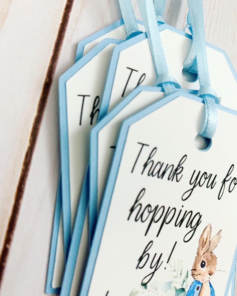 Peter Rabbit "Thank you for hopping by" birthday or baby shower party favor tags. The color of Peter Rabbit's jacket is customizable and can be changed from blue to pink, green or yellow. The background and ribbon will coordinate with Peter Rabbit's Jacket. The text is also customizable.