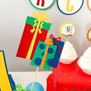 primary colors birthday centerpiece table decor that includes a party hat, number and birthday gifts made of layered cardstock