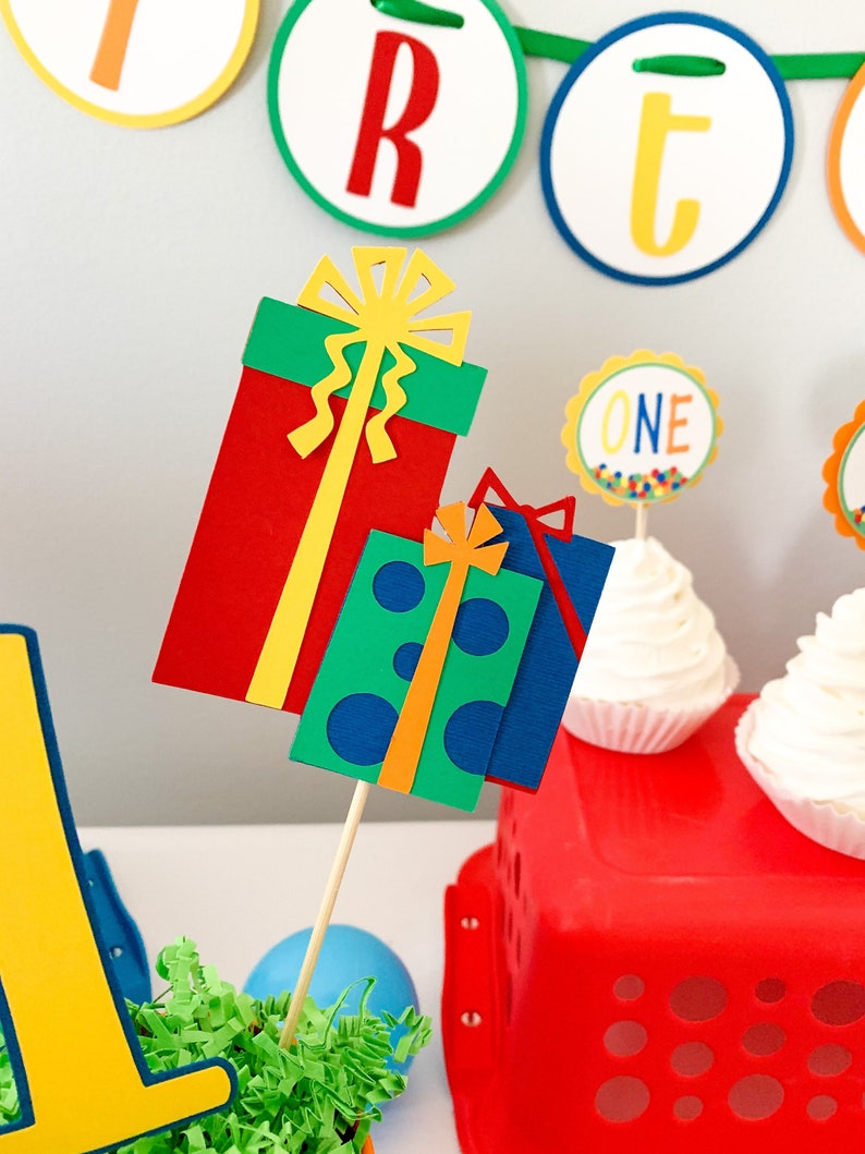 primary colors birthday centerpiece table decor that includes a party hat, number and birthday gifts made of layered cardstock
