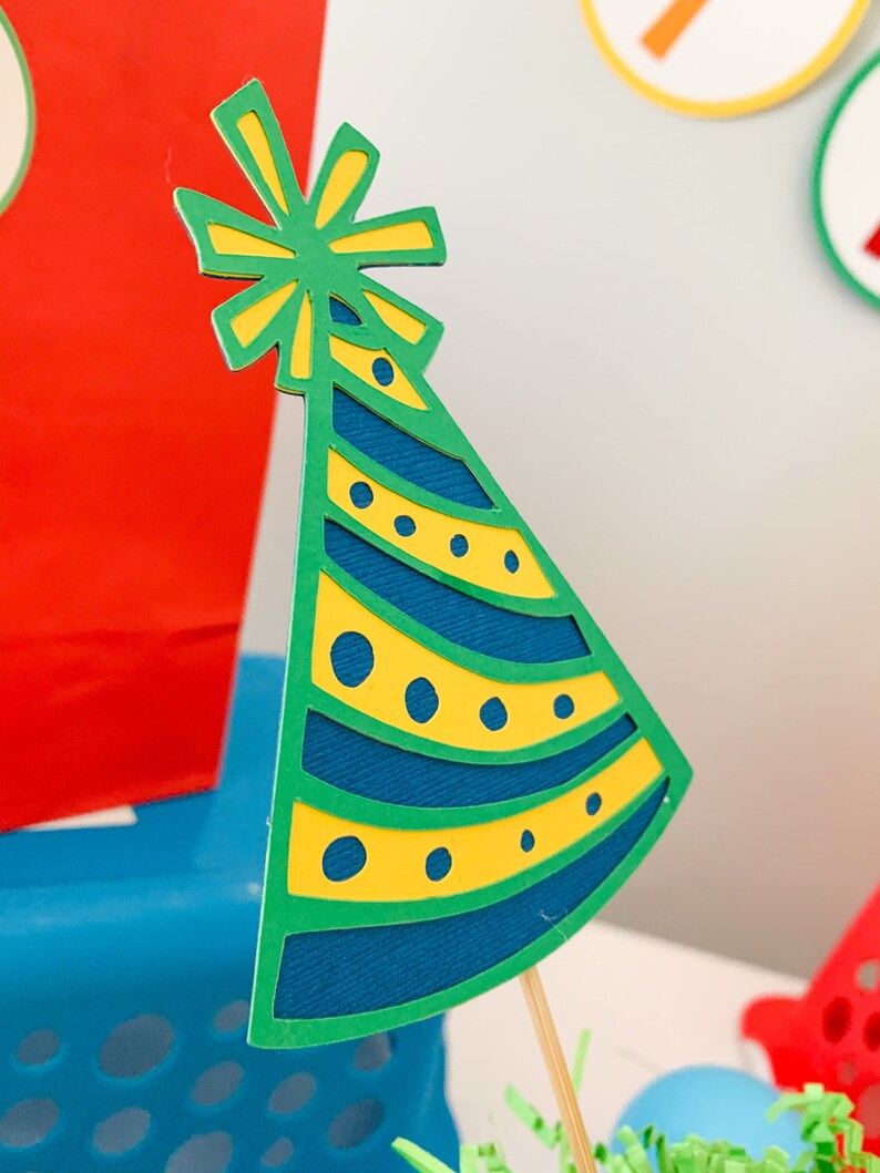 primary colors birthday centerpiece table decor that includes a party hat, number and birthday gifts made of layered cardstock