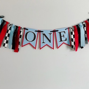 red blue and black racing themed high chair one banner featuring checkered flag fabric