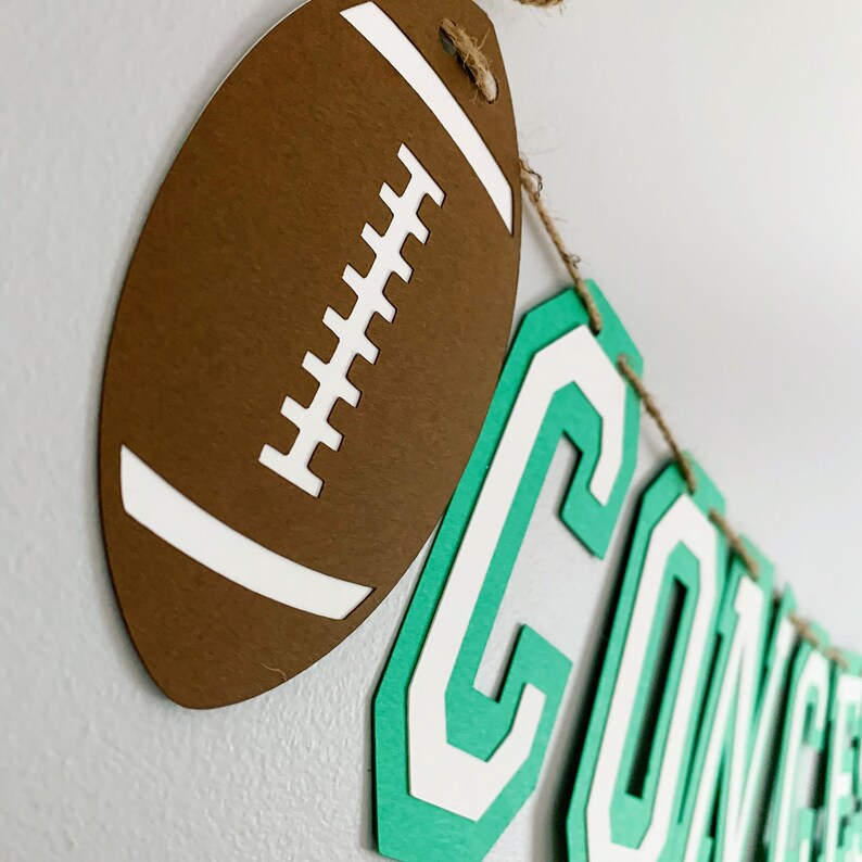 football concessions banner featuring varsity letters and two footballs that will be perfect for your little one's football themed birthday party, super bowl game day party, sports team party or to hang on your schools concession stand during football season. The banner is fully customizable.