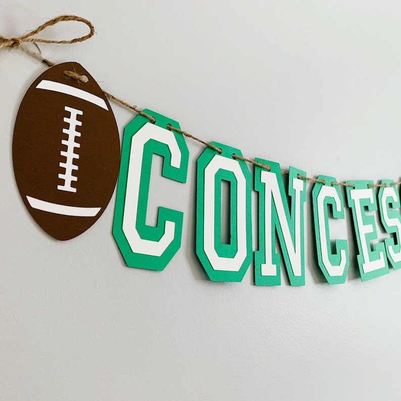 football concessions banner featuring varsity letters and two footballs that will be perfect for your little one's football themed birthday party, super bowl game day party, sports team party or to hang on your schools concession stand during football season. The banner is fully customizable.