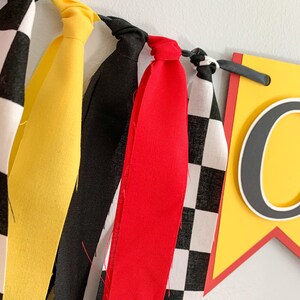 red yellow and black racing themed high chair one banner featuring checkered flag fabric