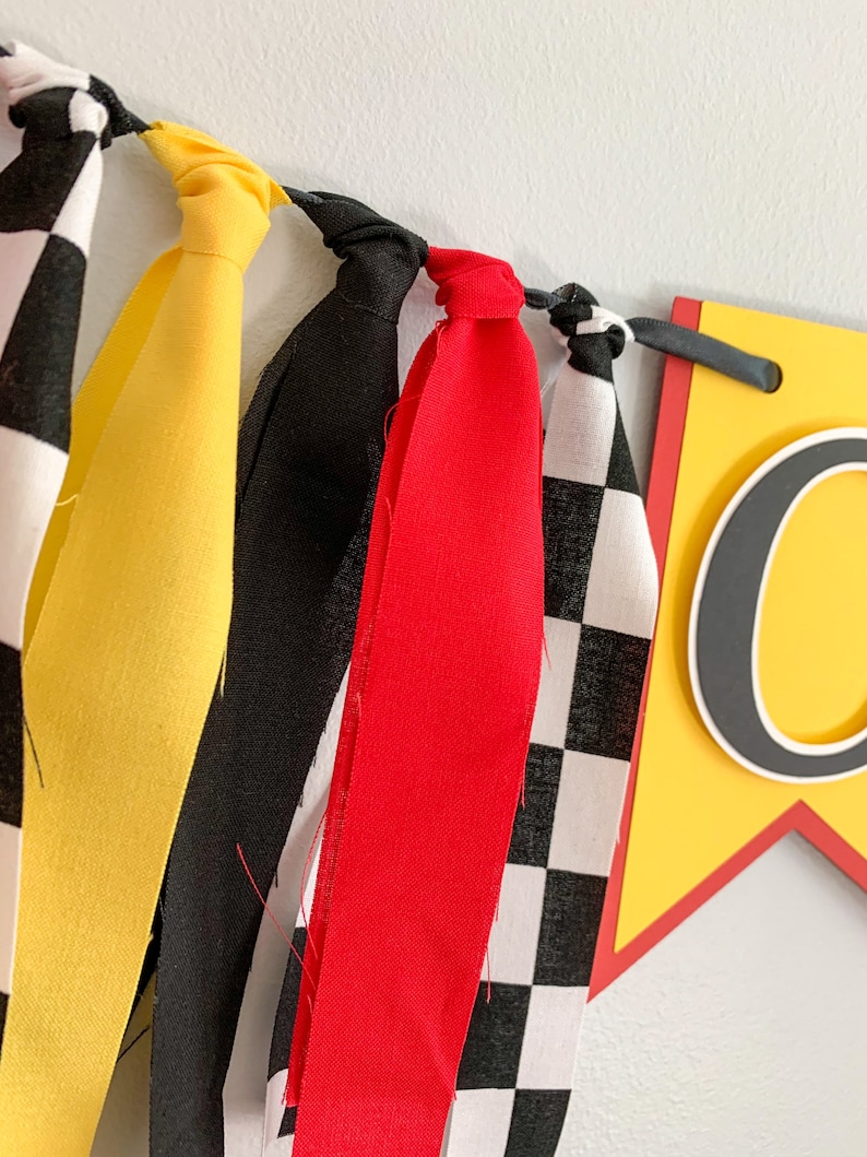 red yellow and black racing themed high chair one banner featuring checkered flag fabric