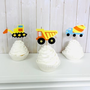 May include: Three cupcakes decorated with construction vehicle toppers. The toppers are a yellow excavator, an orange dump truck, and a blue cement mixer.