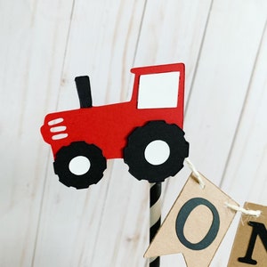 May include: Red and black tractor cake topper with a brown banner that says "One".