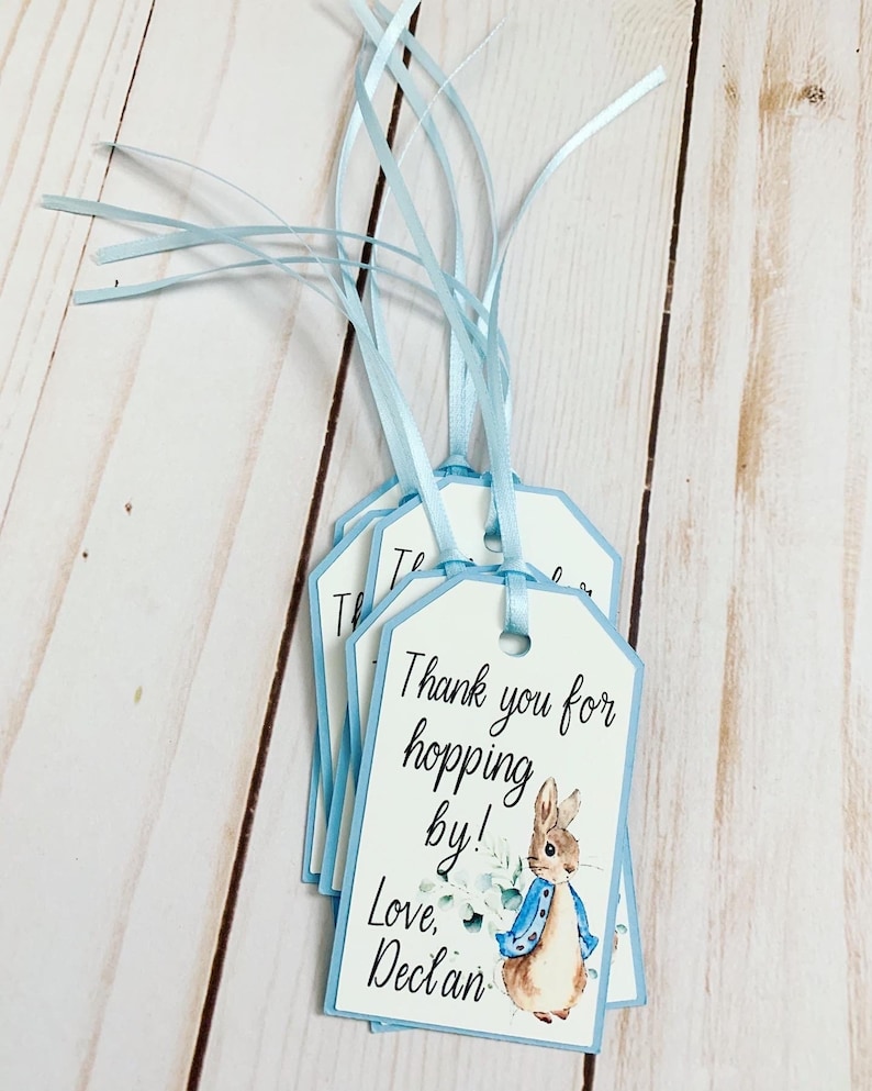 Peter Rabbit "Thank you for hopping by" birthday or baby shower party favor tags. The color of Peter Rabbit's jacket is customizable and can be changed from blue to pink, green or yellow. The background and ribbon will coordinate with Peter Rabbit's Jacket. The text is also customizable.