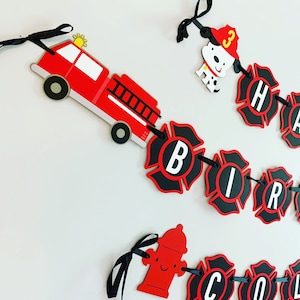 May include: Red and black firefighter themed birthday banner with the words "Happy Birthday" and a fire engine, fire hydrant, and dalmatian dog.