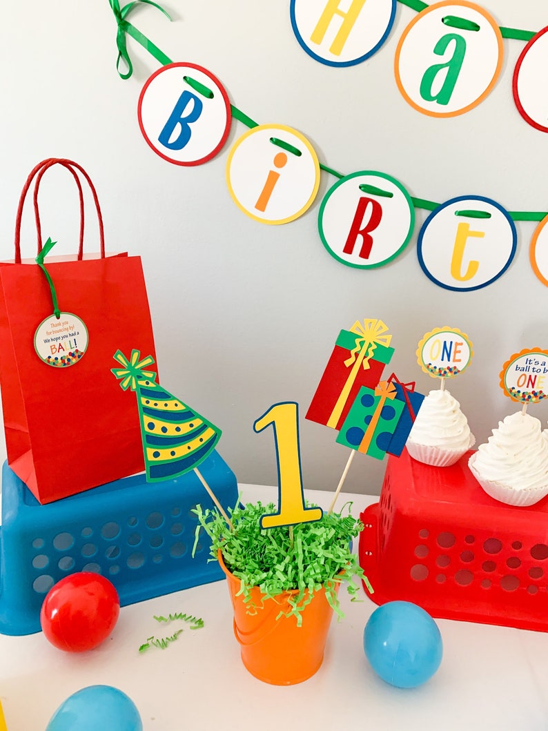 primary colors birthday centerpiece table decor that includes a party hat, number and birthday gifts made of layered cardstock
