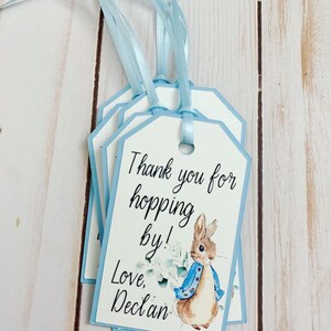 Peter Rabbit "Thank you for hopping by" birthday or baby shower party favor tags. The color of Peter Rabbit's jacket is customizable and can be changed from blue to pink, green or yellow. The background and ribbon will coordinate with Peter Rabbit's Jacket. The text is also customizable.
