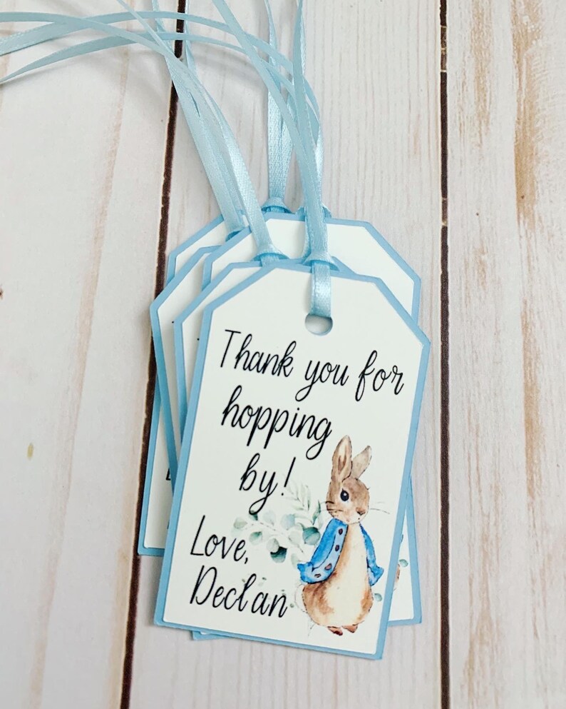 Peter Rabbit "Thank you for hopping by" birthday or baby shower party favor tags. The color of Peter Rabbit's jacket is customizable and can be changed from blue to pink, green or yellow. The background and ribbon will coordinate with Peter Rabbit's Jacket. The text is also customizable.
