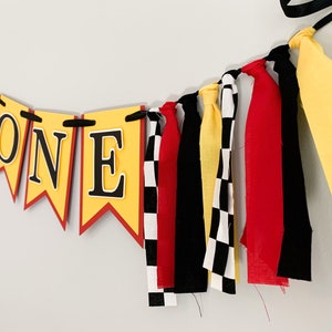 red yellow and black racing themed high chair one banner featuring checkered flag fabric