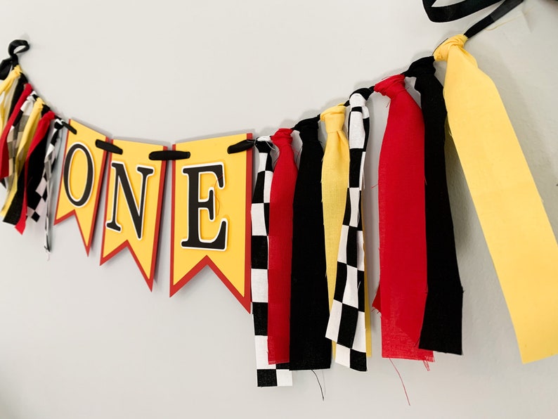 red yellow and black racing themed high chair one banner featuring checkered flag fabric