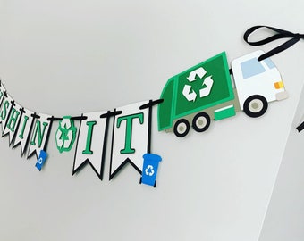 May include: A green and white paper banner with the words "CRUSHIN IT" in black letters. The banner has a green recycling truck and blue recycling bins.