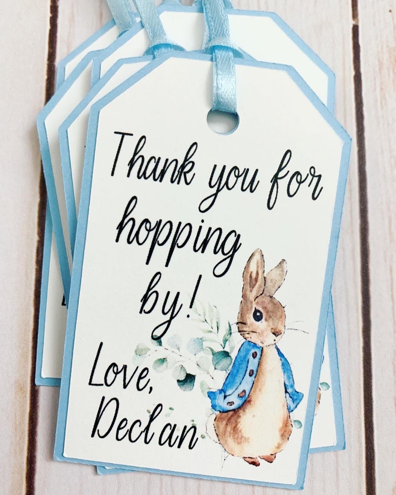 Peter Rabbit "Thank you for hopping by" birthday or baby shower party favor tags. The color of Peter Rabbit's jacket is customizable and can be changed from blue to pink, green or yellow. The background and ribbon will coordinate with Peter Rabbit's Jacket. The text is also customizable.