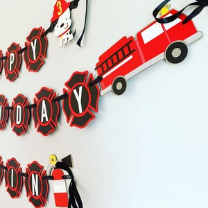 May include: A red fire engine with black wheels and a ladder, a black and red fire hydrant, a black and red fire extinguisher, and a black and red firefighter dog with a red hat and the number 3 on it. The fire engine, fire hydrant, fire extinguisher, and firefighter dog are all part of a black and red banner that says "Happy Birthday".