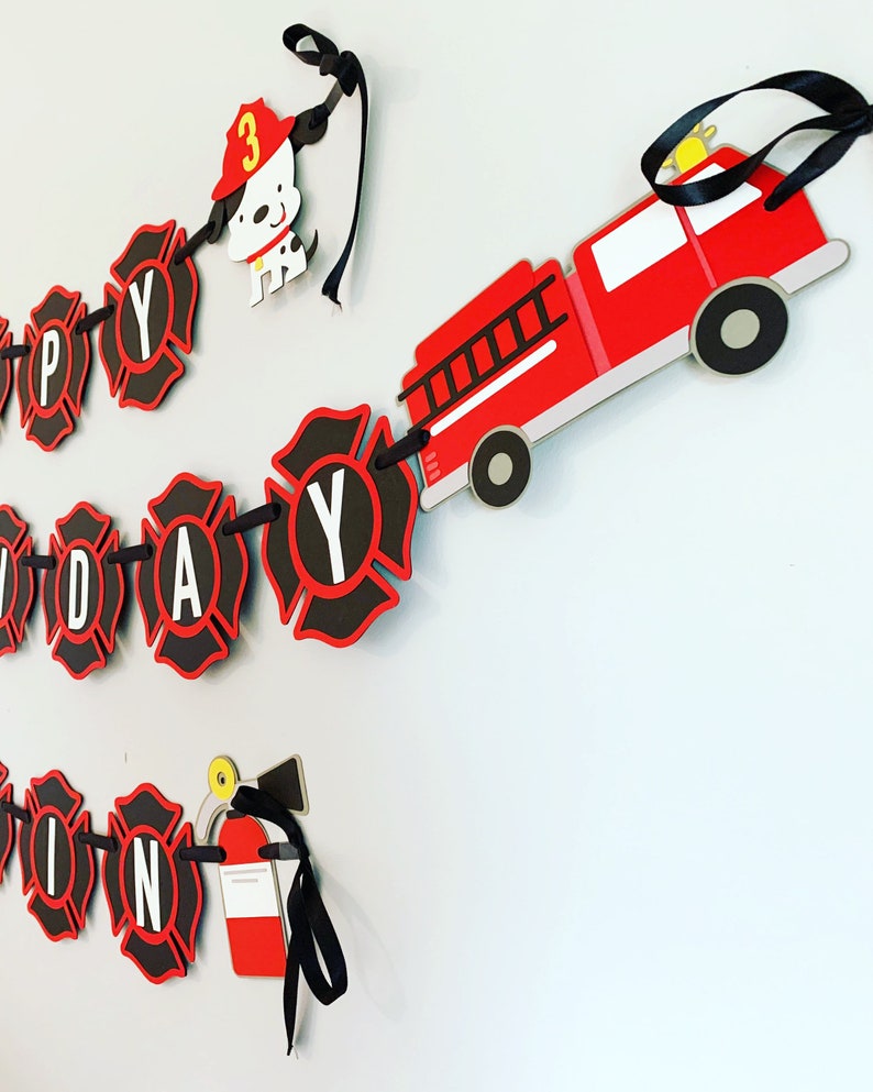 May include: A red fire engine with black wheels and a ladder, a black and red fire hydrant, a black and red fire extinguisher, and a black and red firefighter dog with a red hat and the number 3 on it. The fire engine, fire hydrant, fire extinguisher, and firefighter dog are all part of a black and red banner that says "Happy Birthday".