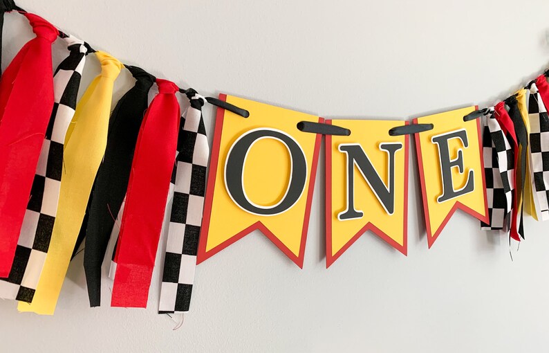 red yellow and black racing themed high chair one banner featuring checkered flag fabric
