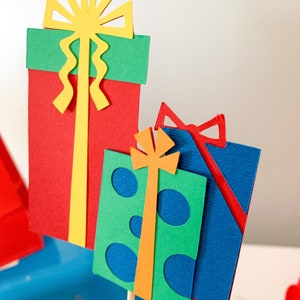 primary colors birthday centerpiece table decor that includes a party hat, number and birthday gifts made of layered cardstock
