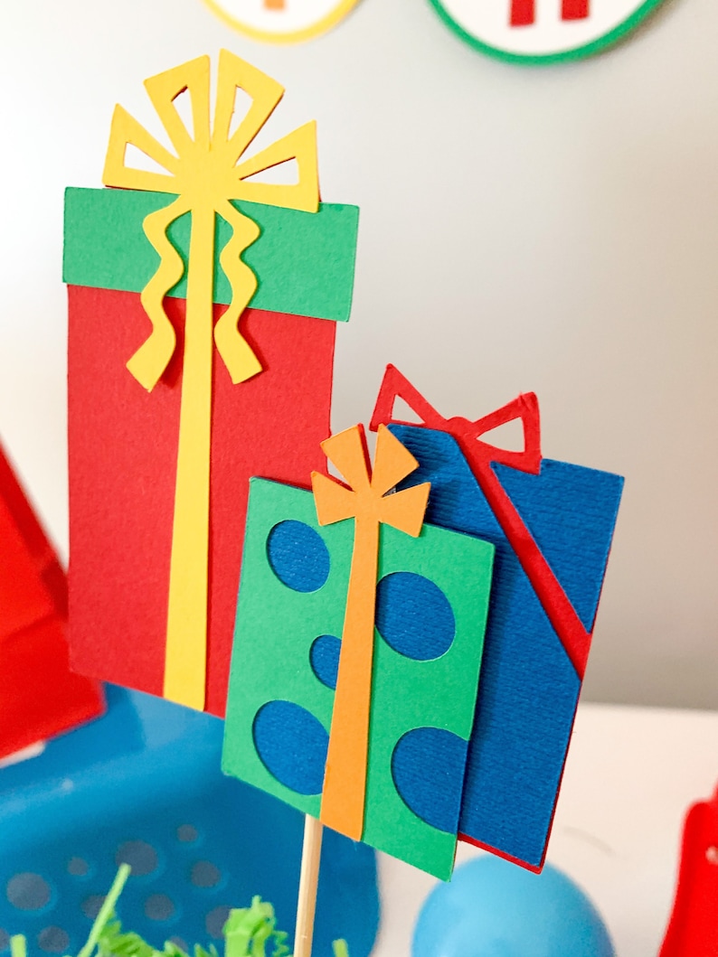 primary colors birthday centerpiece table decor that includes a party hat, number and birthday gifts made of layered cardstock