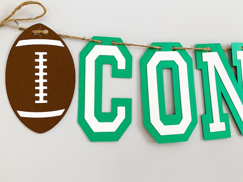 football concessions banner featuring varsity letters and two footballs that will be perfect for your little one's football themed birthday party, super bowl game day party, sports team party or to hang on your schools concession stand during football season. The banner is fully customizable.