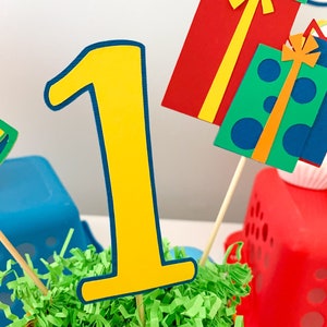 primary colors birthday centerpiece table decor that includes a party hat, number and birthday gifts made of layered cardstock