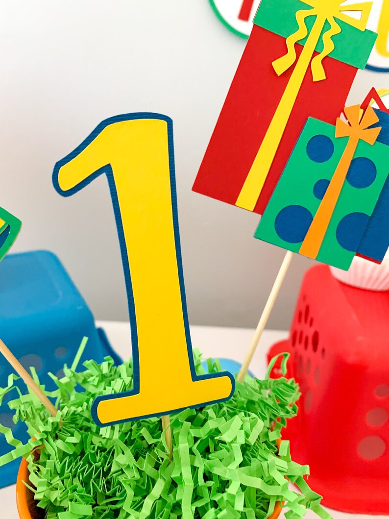 primary colors birthday centerpiece table decor that includes a party hat, number and birthday gifts made of layered cardstock