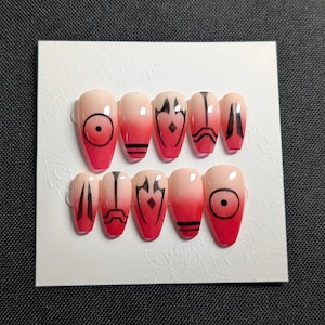May include: A set of press-on nails with a gradient design, transitioning from a nude pink to a vibrant red. Each nail features black geometric patterns, including circles, lines, and stylized shapes. The nails are arranged on a white card.