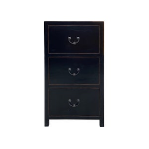 May include: A black wooden three-drawer chest with antique-style metal handles.